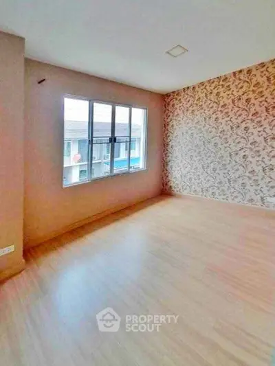 Spacious empty room with large window and decorative wall, ideal for customization.