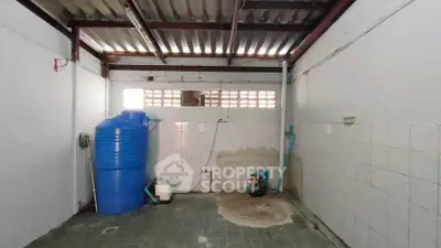 Spacious utility area with water tank and tiled flooring, ideal for storage or laundry setup.