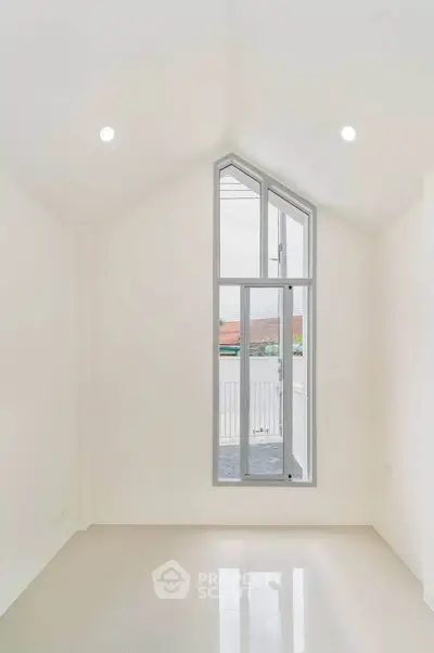 Bright minimalist room with high ceiling and large window, perfect for modern living.