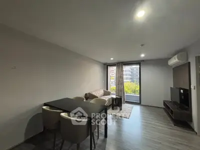 Modern living room with balcony view, sleek furniture, and ample natural light in urban apartment.