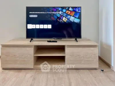 Modern living room with sleek wooden TV stand and large flat-screen television.
