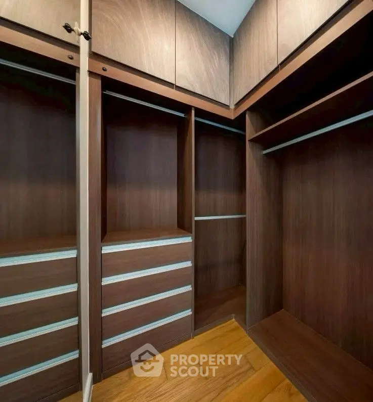 Spacious walk-in closet with wooden shelves and drawers, perfect for organized storage.