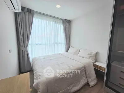Cozy bedroom with large window and modern furnishings in a bright apartment.