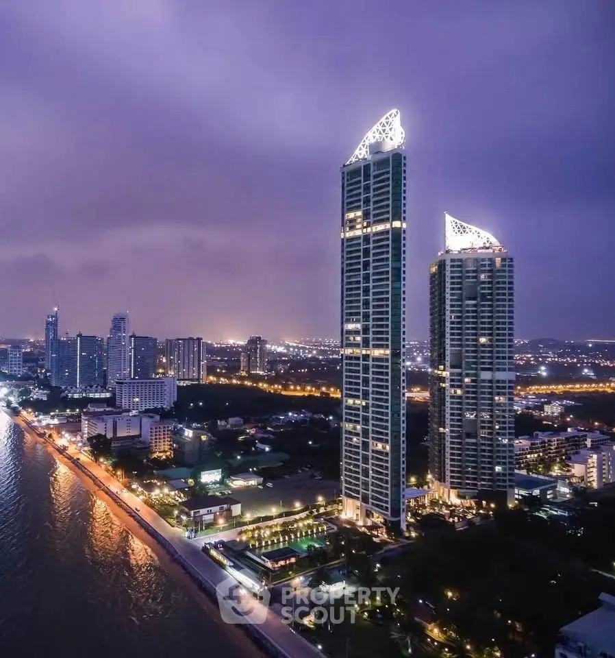 Stunning night view of luxury high-rise buildings by the waterfront in a vibrant cityscape.