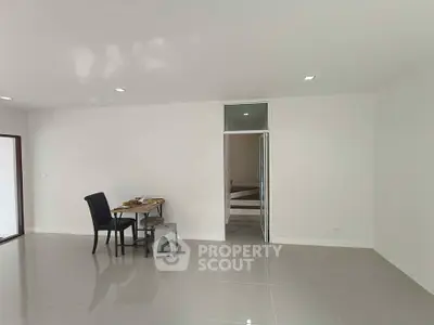 Spacious minimalist living room with sleek tile flooring and modern furniture.