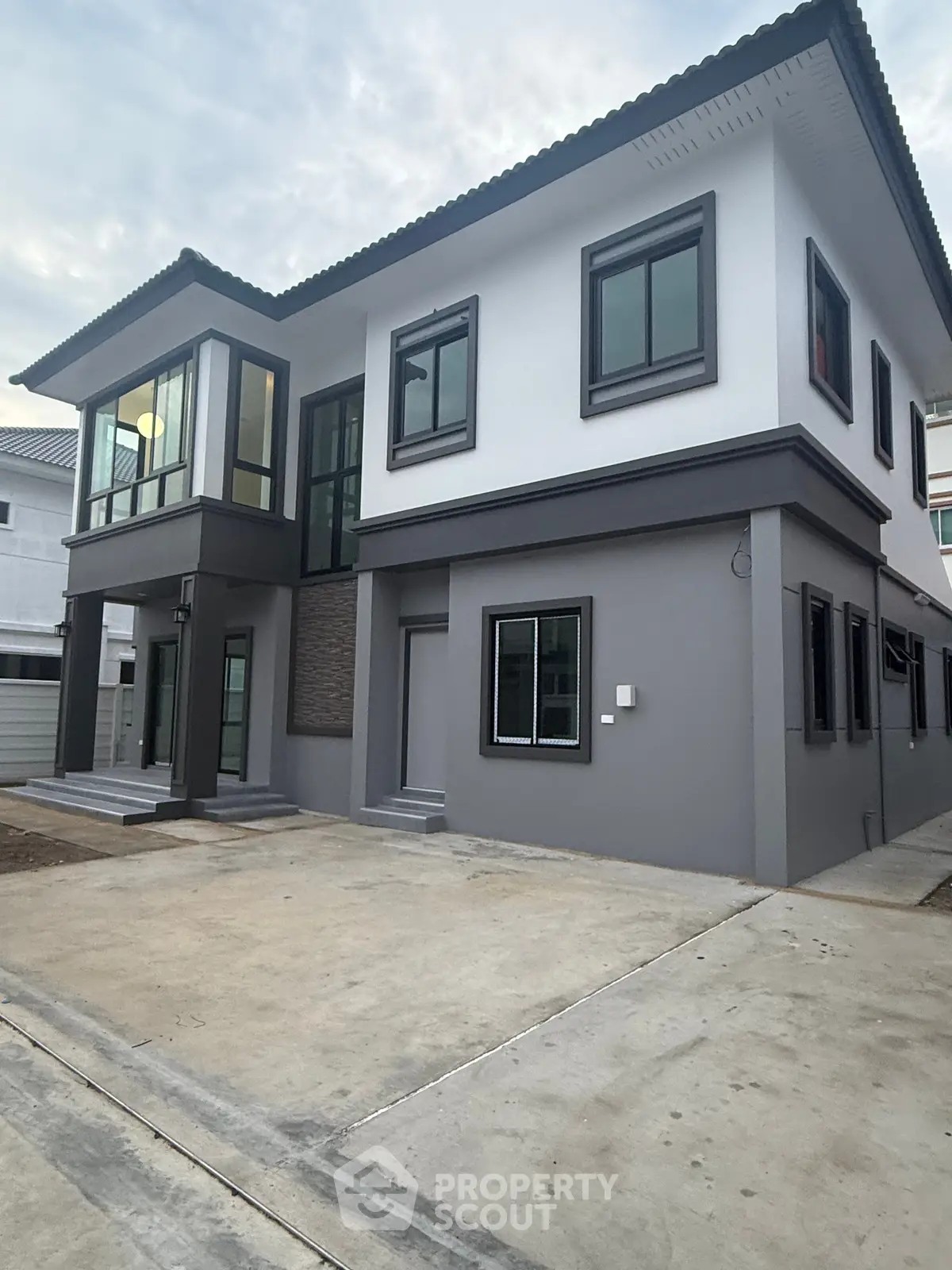 Modern two-story house with sleek design and large windows in a suburban neighborhood.
