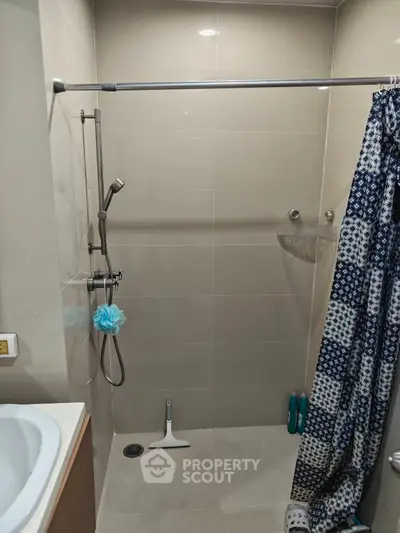 Modern bathroom with shower and patterned curtain in sleek design.