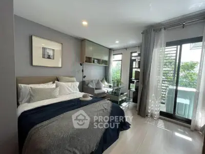Modern bedroom with cozy seating area and balcony view, perfect for urban living.