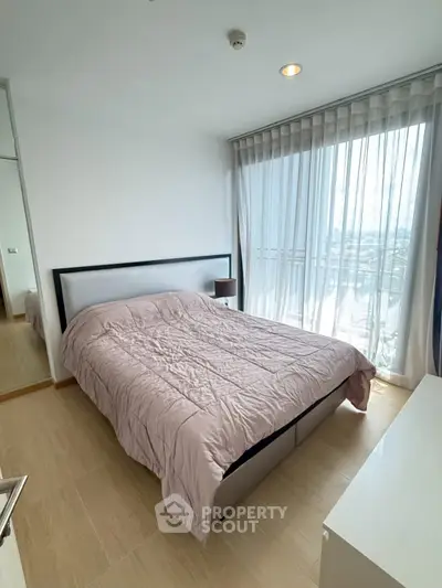 Bright bedroom with large window and modern decor in a high-rise apartment.