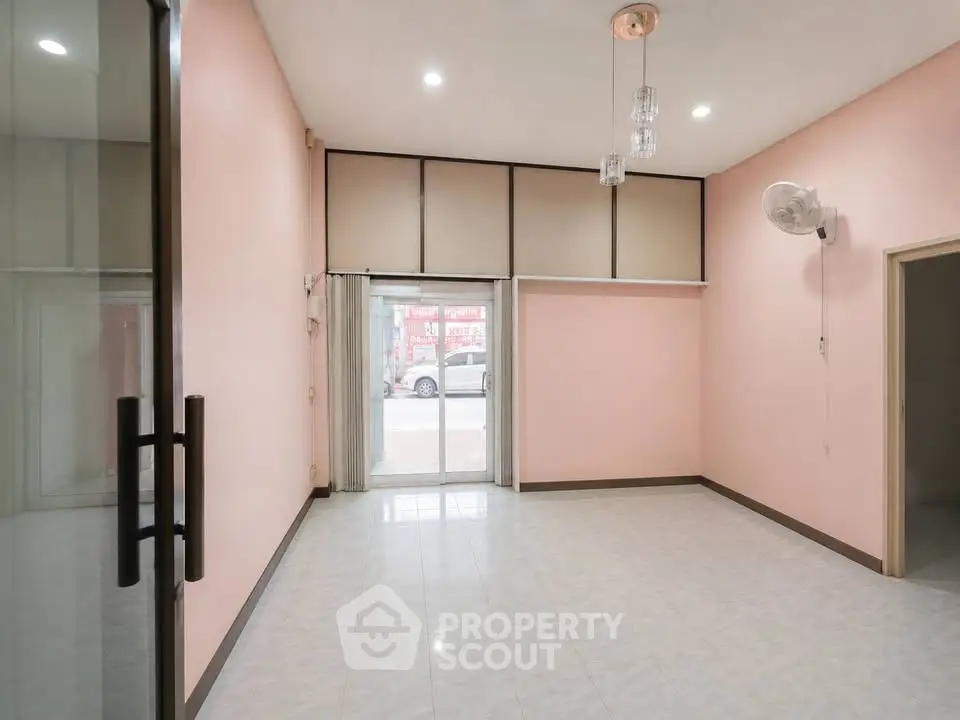 Spacious empty room with pink walls and large window, ideal for customization.