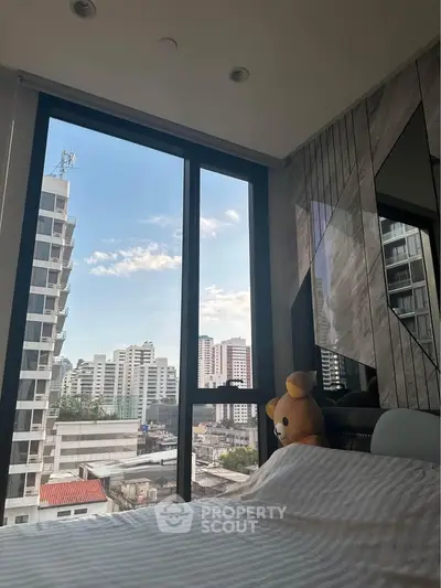 Modern bedroom with large window offering stunning city view and stylish decor