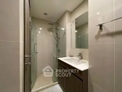 Modern bathroom with glass shower and sleek vanity in contemporary apartment.