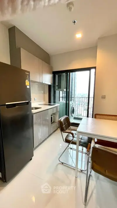 Modern kitchen with sleek appliances and dining area in high-rise apartment with city view.