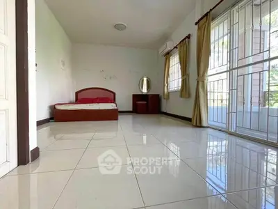 Spacious bedroom with tiled flooring and natural light, featuring a bed and vanity set.