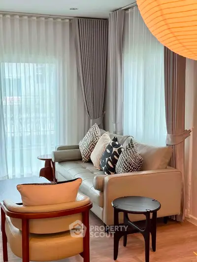 Elegant living room with stylish furniture and large windows with sheer curtains.