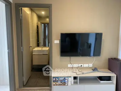 Modern living room with wall-mounted TV and view into a sleek bathroom, showcasing contemporary design.