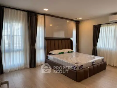 Spacious bedroom with elegant decor and large windows for natural light.