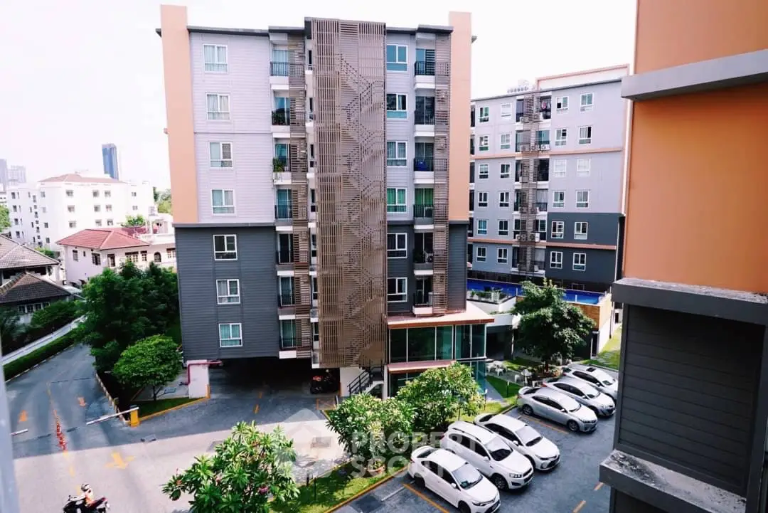 Modern apartment building with parking and lush greenery in urban setting.