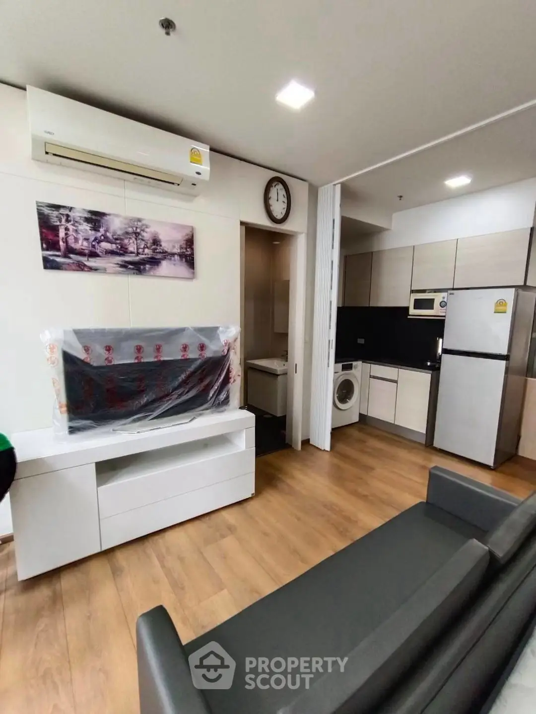 Modern living room with sleek kitchen, featuring hardwood floors and contemporary appliances.