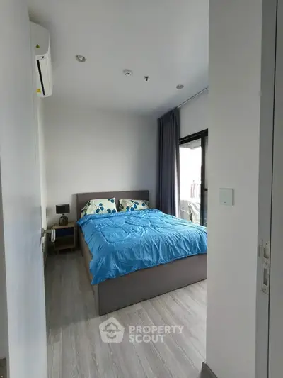 Cozy bedroom with modern decor and large window offering natural light.