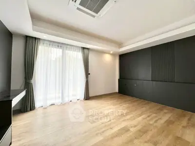 Spacious modern living room with elegant wood flooring and large window for natural light.
