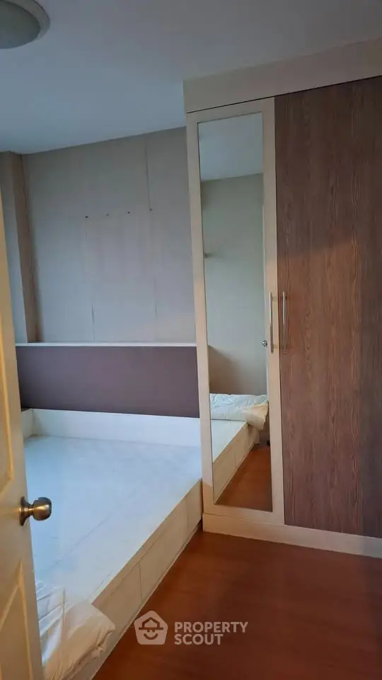 Cozy bedroom with built-in wardrobe and wooden flooring, perfect for modern living.