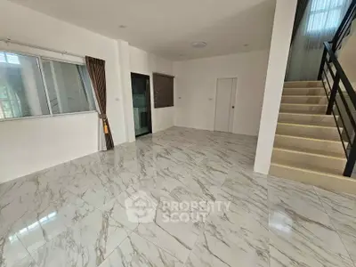Spacious modern living room with marble flooring and staircase in a stylish home.