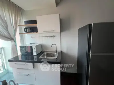 Modern compact kitchen with sleek cabinetry and appliances in a bright apartment.