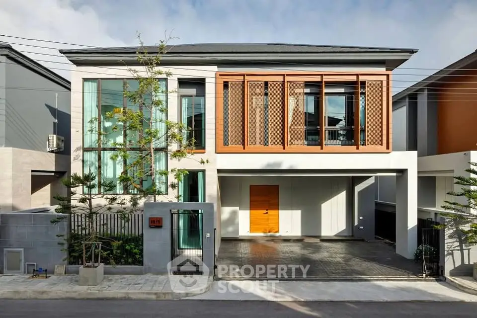 Modern two-story house with sleek design and large windows, featuring a spacious driveway and contemporary facade.