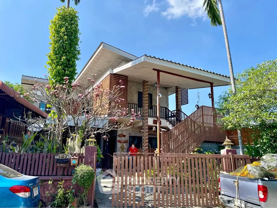 Charming two-story house with lush garden and wooden accents under clear blue sky.