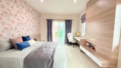 Charming bedroom with floral wallpaper and cozy decor, featuring a stylish desk and large window.