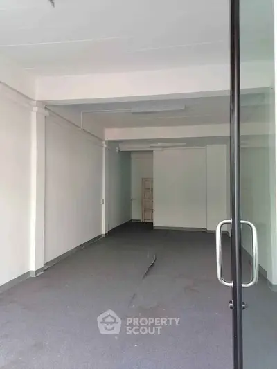 Spacious empty commercial space with glass door entry, ideal for retail or office setup.
