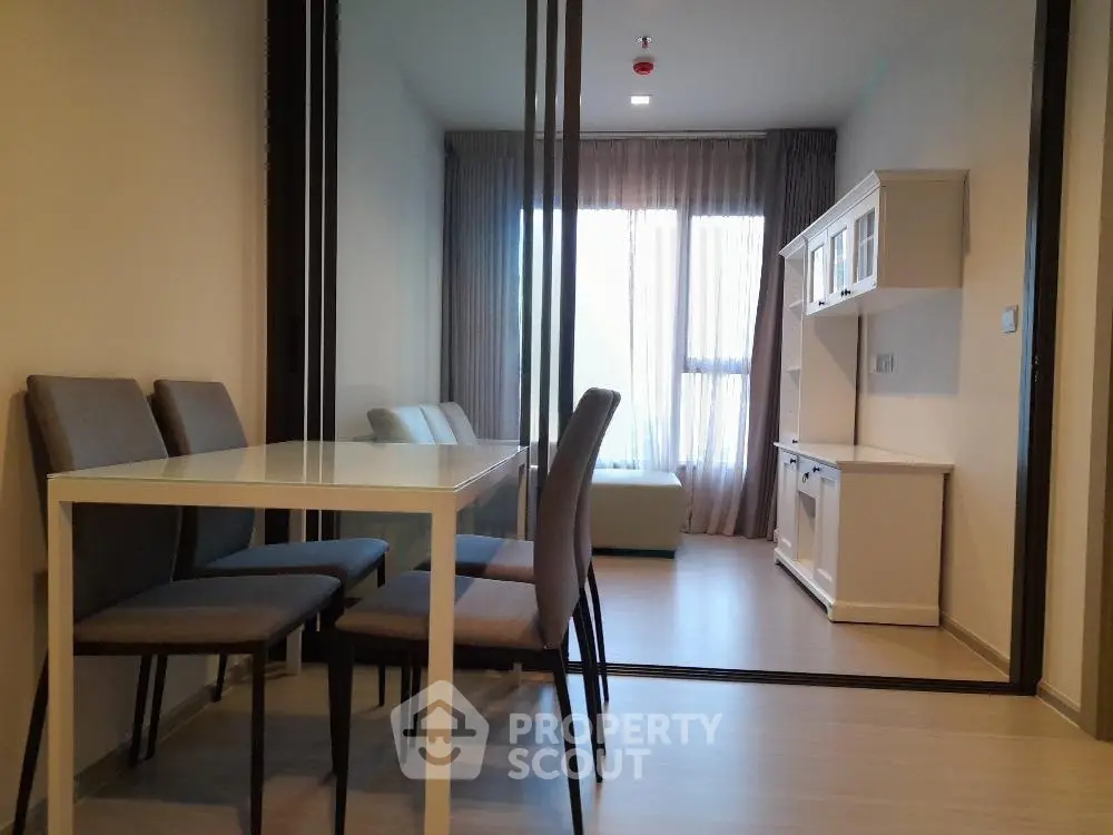 Modern dining area with sleek table and chairs, adjacent to a cozy living space with natural light.