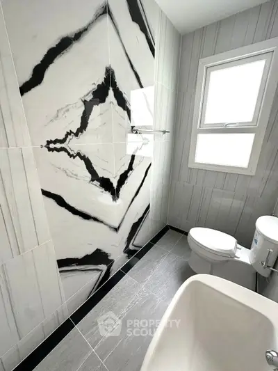 Modern bathroom with striking black and white marble wall tiles and sleek fixtures.