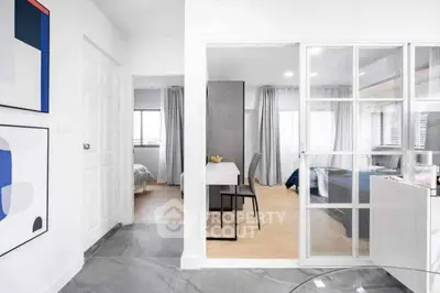 Modern apartment interior with glass partition, stylish decor, and bright natural lighting.