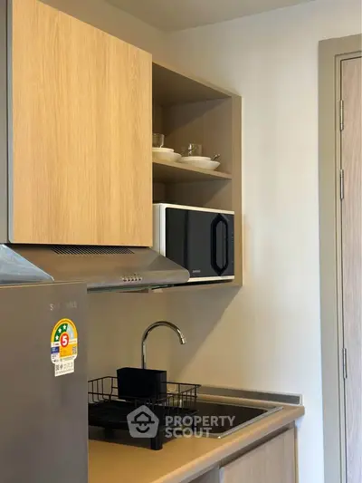 Modern kitchen with sleek appliances and open shelving in a stylish apartment.