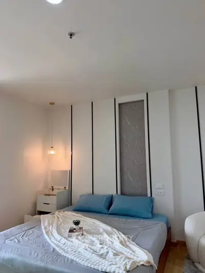 Cozy bedroom with modern decor and soft lighting, featuring a comfortable bed and stylish bedside table.