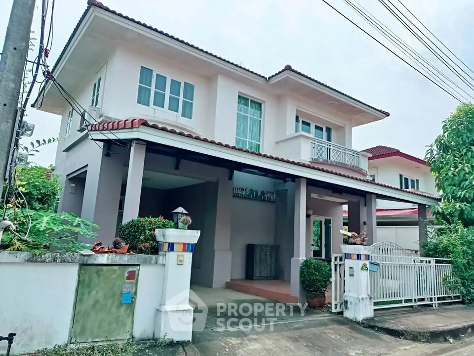 Charming two-story house with gated entrance and lush greenery