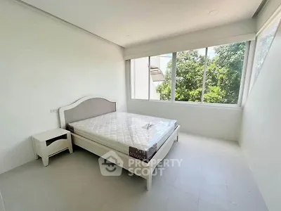 Bright minimalist bedroom with large windows and serene garden view