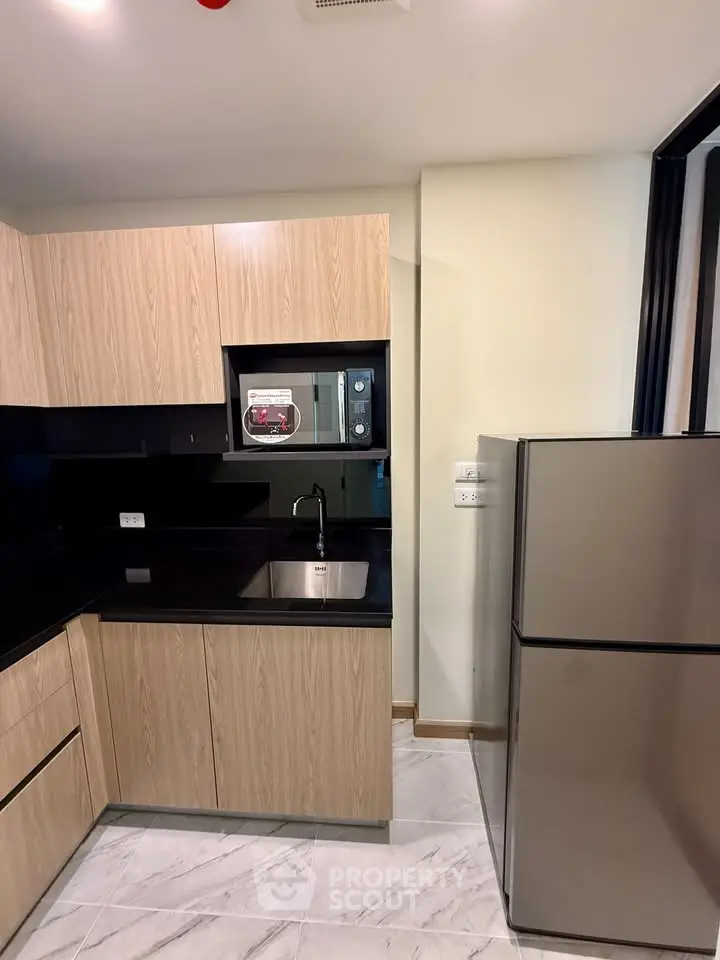 Modern kitchen with sleek wooden cabinets and stainless steel appliances in a stylish apartment.