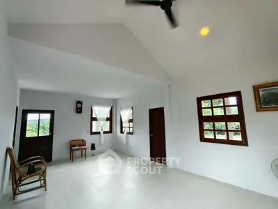 Spacious living room with high ceiling and large windows offering natural light and scenic views.