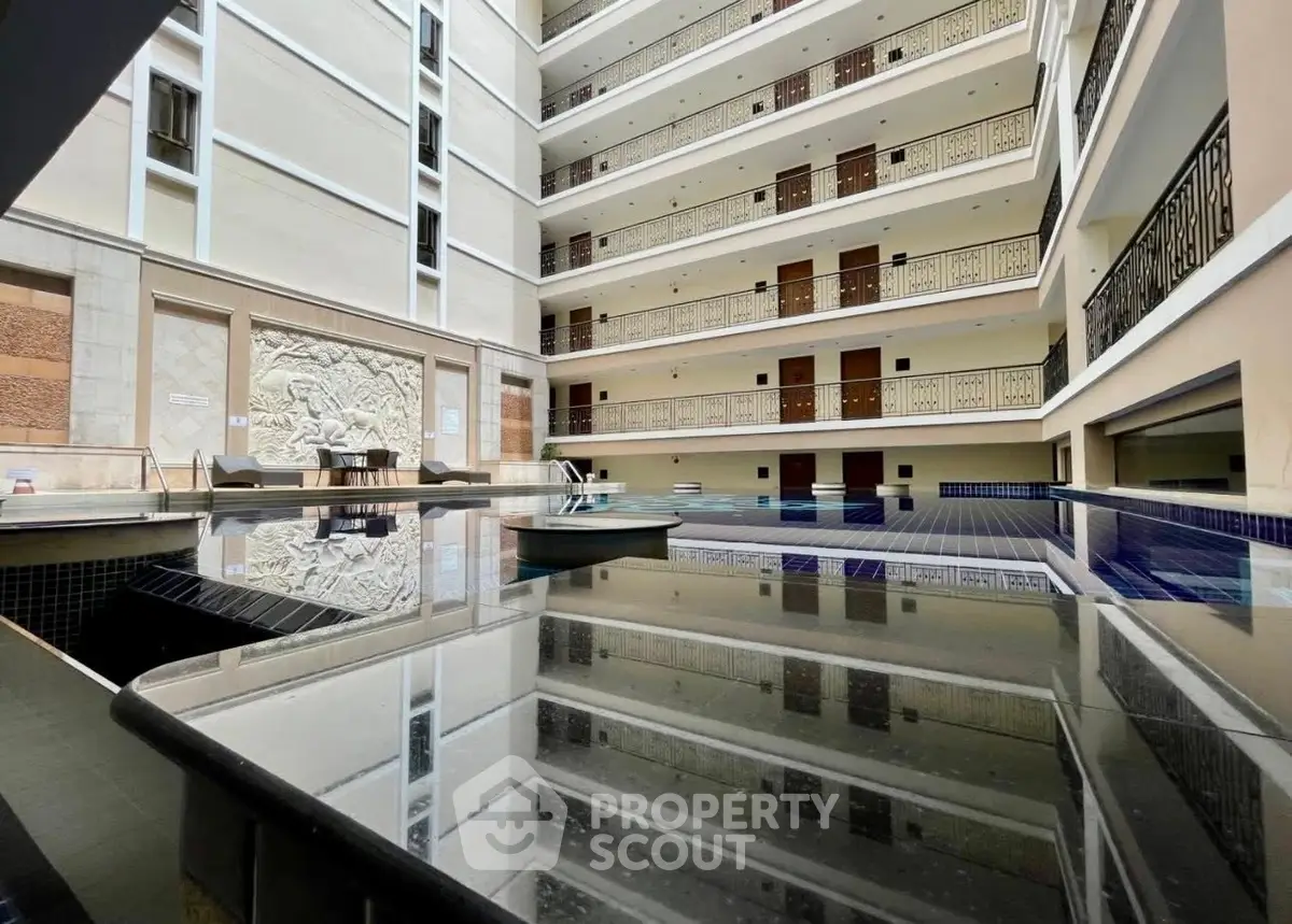 Luxurious indoor pool area in modern apartment building with elegant balconies and artistic wall decor.