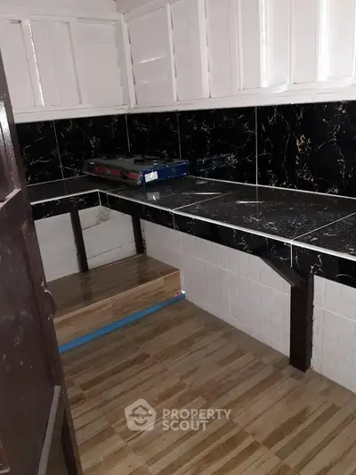 Compact kitchen with black marble countertops and white cabinets