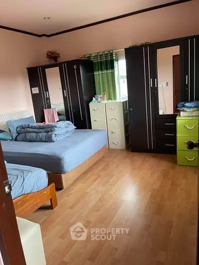 Spacious bedroom with wooden flooring and ample storage in a cozy home.