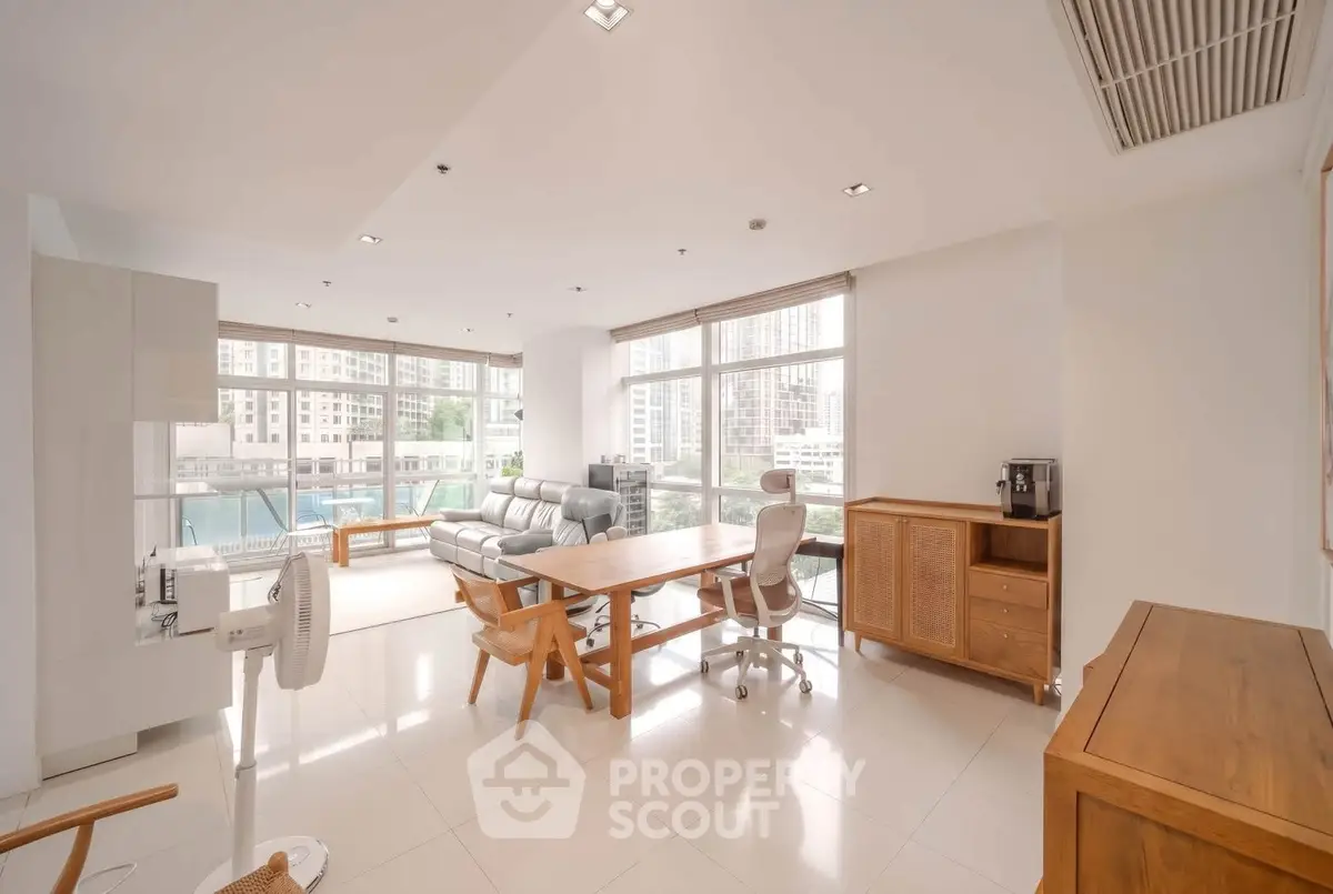 Spacious modern living room with large windows and elegant furniture in a high-rise apartment.
