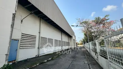 Industrial warehouse exterior with spacious driveway and secure fencing
