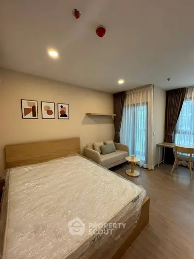 Modern bedroom with cozy seating area and natural light in stylish apartment.