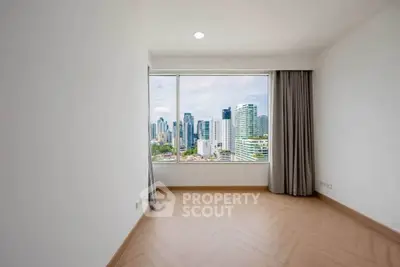 Spacious empty room with large window offering stunning city skyline view.