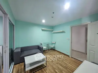 Modern living room with teal walls, sleek furniture, and wooden flooring in a cozy apartment.