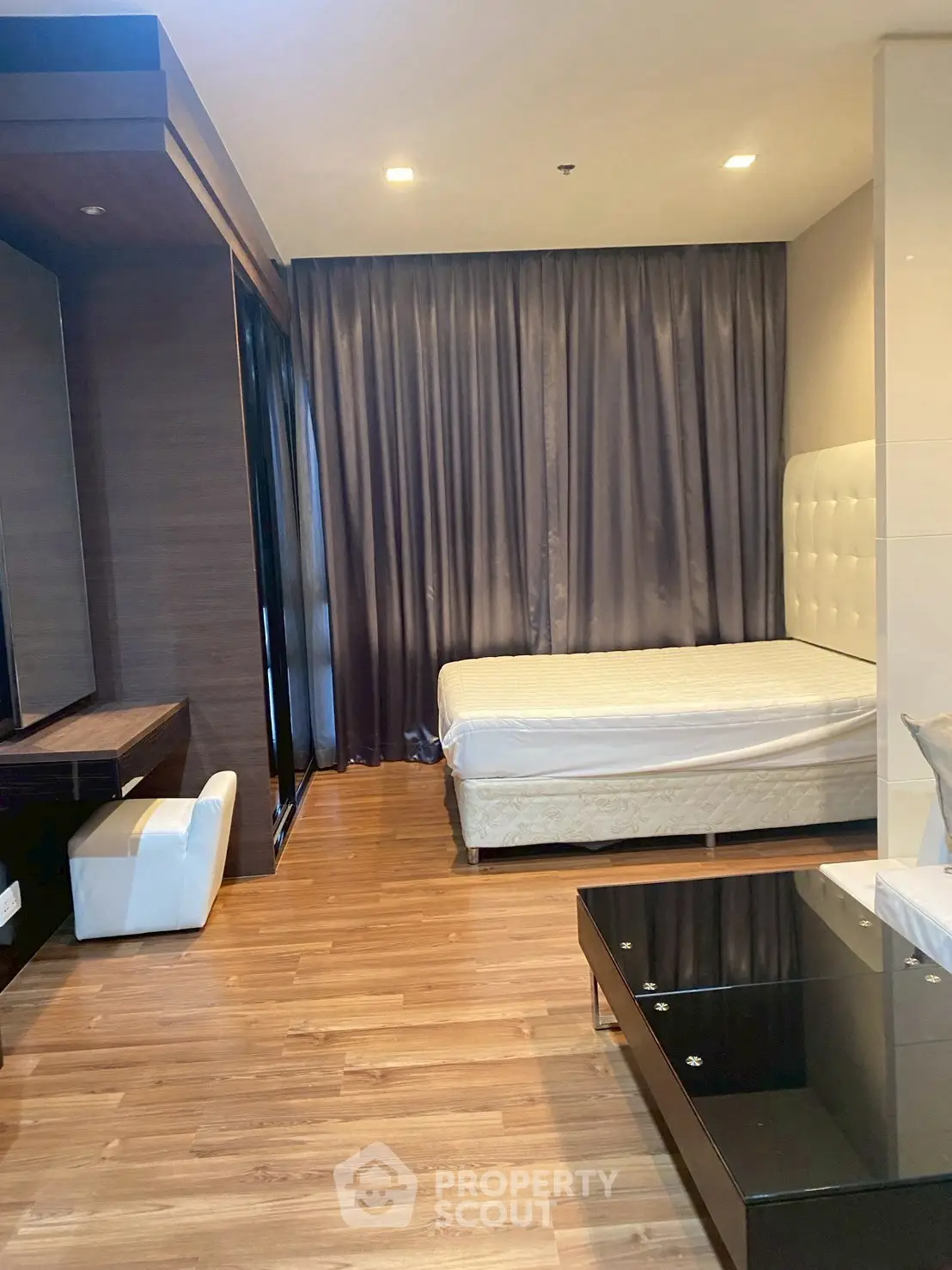 Modern bedroom with wooden flooring and elegant curtains in a stylish apartment.